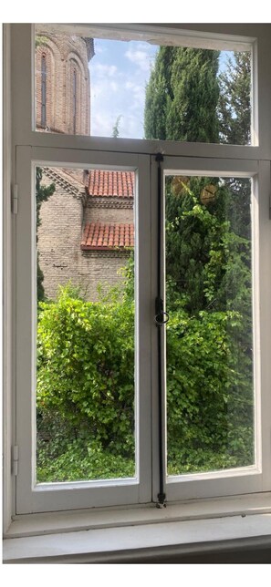 Ein Fenster mit Blick auf ein Ziegelgebäude und Grünflächen.