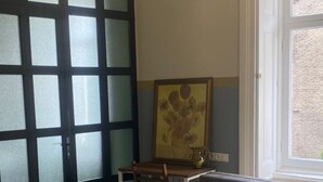 A room with a grey sofa, a wooden floor, a window, and a door with frosted glass panels. - NinasPlace3 (T'bilisi)