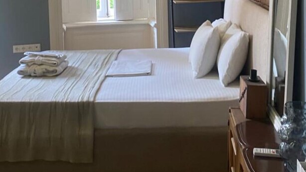 A single bed with a headboard, a bedside table, a mirror, and a ceiling light fixture. - NinasPlace3 (T'bilisi)