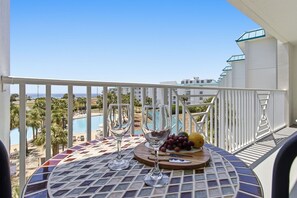 Ein Balkon mit einem Tisch für zwei Personen, mit Blick auf einen Pool und Gebäude.