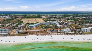 Oversigtsbillede af en kystferie med flere hotelbygninger, en strand og en lysthavn.