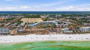 Ein Luftbild eines Küstenresorts mit mehreren Hotelgebäuden, einem Strand und einer Marina.