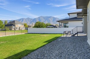 A residential property with a well-maintained lawn, a gravel patio, and a view of mountains in the background. - Mountain View Home with Large Yard Near Salt Lake (Stansbury Park)
