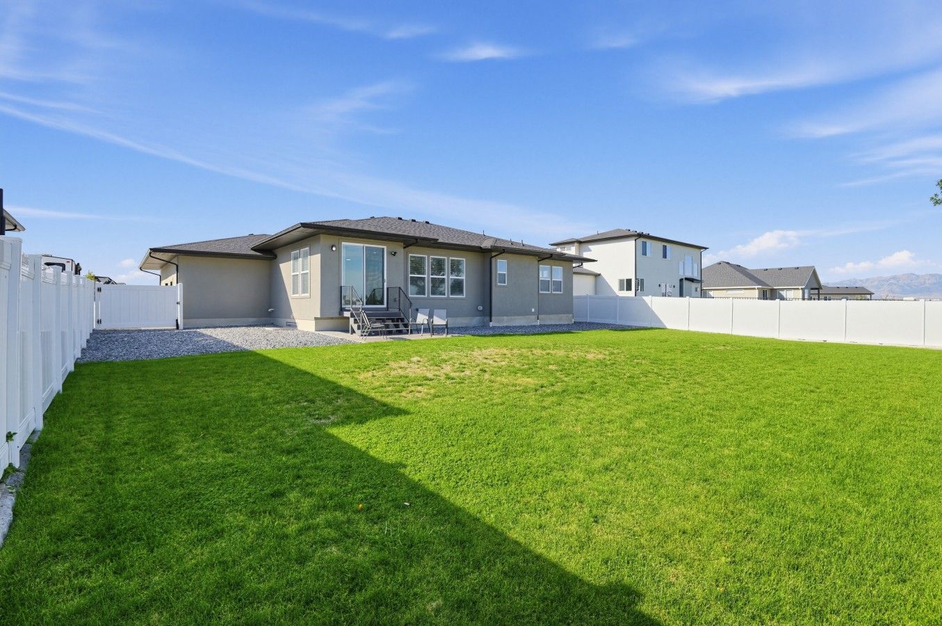 A residential property with a well-maintained lawn, a fenced backyard, and a two-story house with a visible front porch and windows.