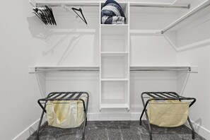 A walk-in closet with a central hanging rod, two metal drying racks, and a shelf unit. - Mountain View Home with Large Yard Near Salt Lake (Stansbury Park)