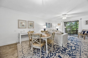 Un coin repas avec une table ronde, des chaises, un canapé blanc et un tapis bleu à motifs.