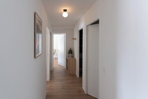 Ein Flur mit Holzdielen, weißen Wänden und einer Deckenleuchte.