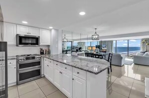 A modern kitchen with white cabinetry, a large island, stainless steel appliances, and a view of the ocean. - “Castle in the Sky • Ocean Views
Penthouse (Myrtle Beach)