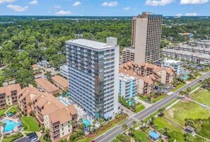 A high-rise building with multiple floors, surrounded by other residential buildings and greenery. - “Castle in the Sky • Ocean Views
Penthouse (Myrtle Beach)