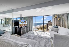 A modern living room with a large TV, comfortable seating, and a view of the beach. - “Castle in the Sky • Ocean Views
Penthouse (Myrtle Beach)