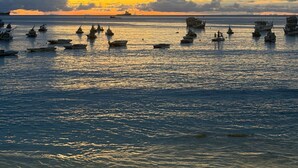 Escena costera con barcos y embarcaciones al atardecer.