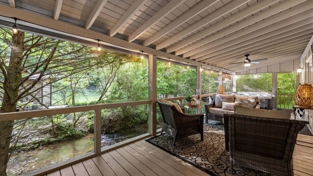 Uma área de estar coberta ao ar livre com móveis de vime, uma mesa e vista para a paisagem natural.