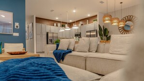 Ein modernes Wohnzimmer mit einem beigen Sofa, einer blauen Decke und einem Holztisch.