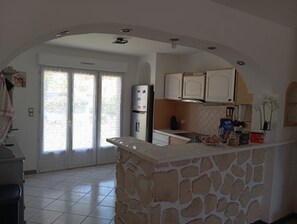 A kitchen with a stone island, white cabinets, a refrigerator, and a view through a glass door. - Villa Cailar: Comfort, Sun and Escape between Nîmes and Montpellier (Le Cailar)