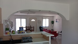 Cozinha com pia, armários e área de refeições com cadeiras e mesa.