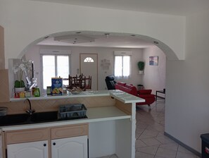 A kitchen with a sink, cabinets, and a dining area with chairs and a table. - Villa Cailar: Comfort, Sun and Escape between Nîmes and Montpellier (Le Cailar)