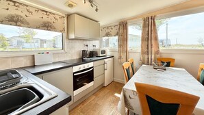 A compact kitchen with a sink, stove, microwave, and dining table with chairs.