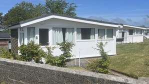 A single-story mobile home with a gabled roof, large windows, and a small porch area.