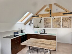A modern kitchen with a skylight, wooden beams, and a dining area. - One bed Character Cottage with Parking and Garden (East Portlemouth)