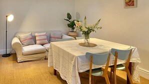 Ein gemütliches Wohnzimmer mit einer Couch, einem Esstisch und einer Stehlampe.