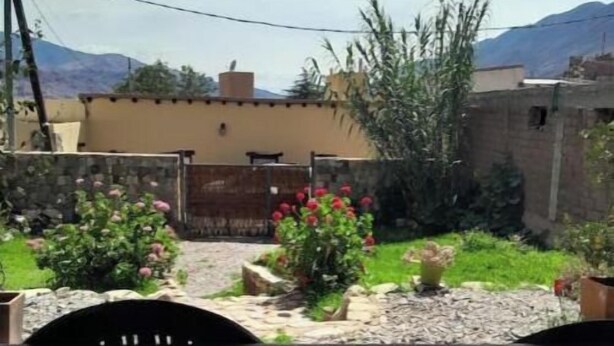 Ein Innenhof mit einer Steinmauer, einem Holztor und einem kleinen Garten mit Blumen.