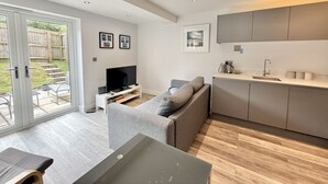 Ein modernes Wohnzimmer mit einer Couch, einem Fernseher und einem Esstisch.