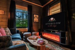 Ein gemütliches Wohnzimmer mit Kamin, Fernseher und einer Couch.
