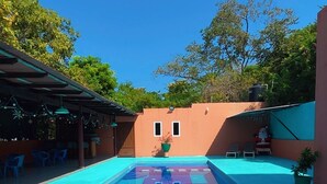 A swimming pool with a tiled deck, surrounded by outdoor seating and potted plants.