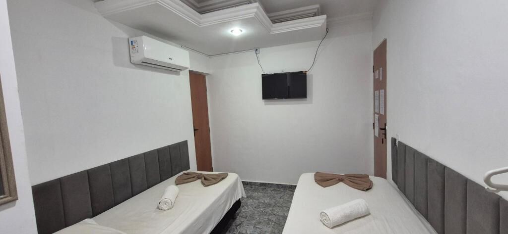 Une chambre d’hôtel avec deux lits, un téléviseur à écran plat, un système de climatisation et une porte en bois.