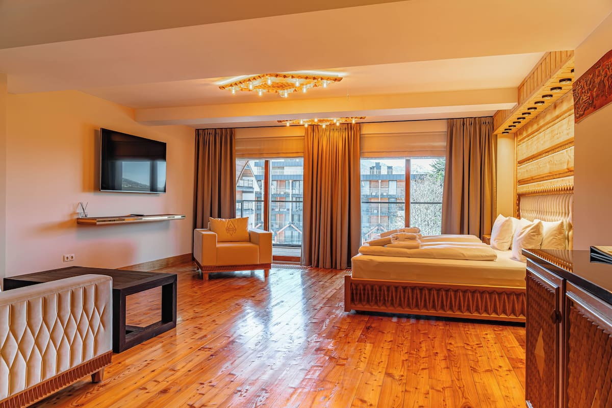 Ein Hotelzimmer mit Bett, einer Couch, einem Fernseher und einem Fenster mit Vorhängen.