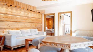 A modern living room with a wooden wall panel, a white sofa, a wooden coffee table, and a large mirror. - Mountain Diamond Resort (Zakopane)