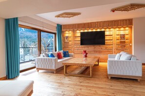 A modern living room with a large TV, wooden paneling, and a sofa with cushions. - Mountain Diamond Resort (Zakopane)