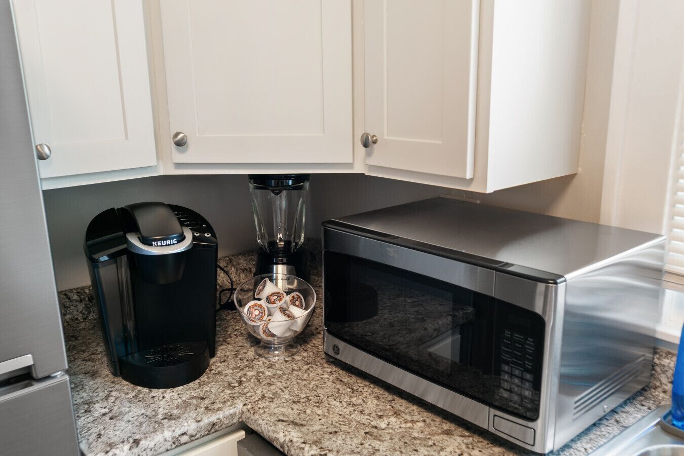 A kitchen with white cabinets, a coffee maker, a blender, and a microwave.