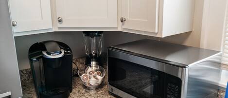 A kitchen with white cabinets, a coffee maker, a blender, and a microwave.