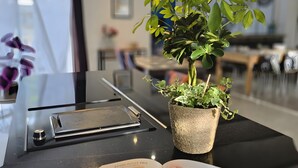 Een moderne keuken met een zwart aanrecht, een potplant en een open keukenhandschrift.