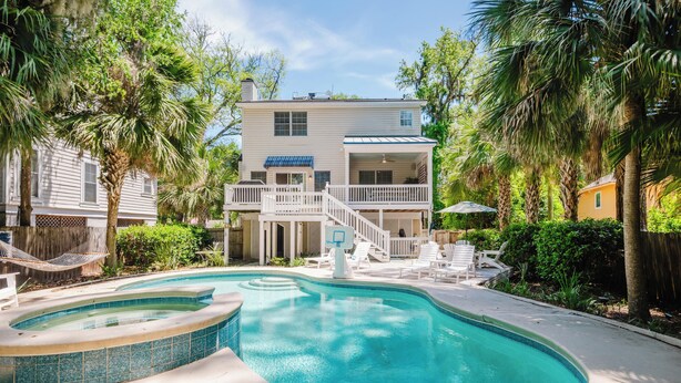 Ein zweistöckiges Haus mit Pool, Terrasse und überdachter Veranda.