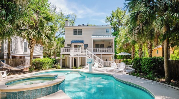 Ein zweistöckiges Haus mit Pool, Terrasse und überdachter Veranda.