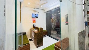 A hotel lobby with a reception desk, a glass partition, and a ceiling with circular light fixtures. - Hotel Vrinda Nikunj Dham (Vrindavan)