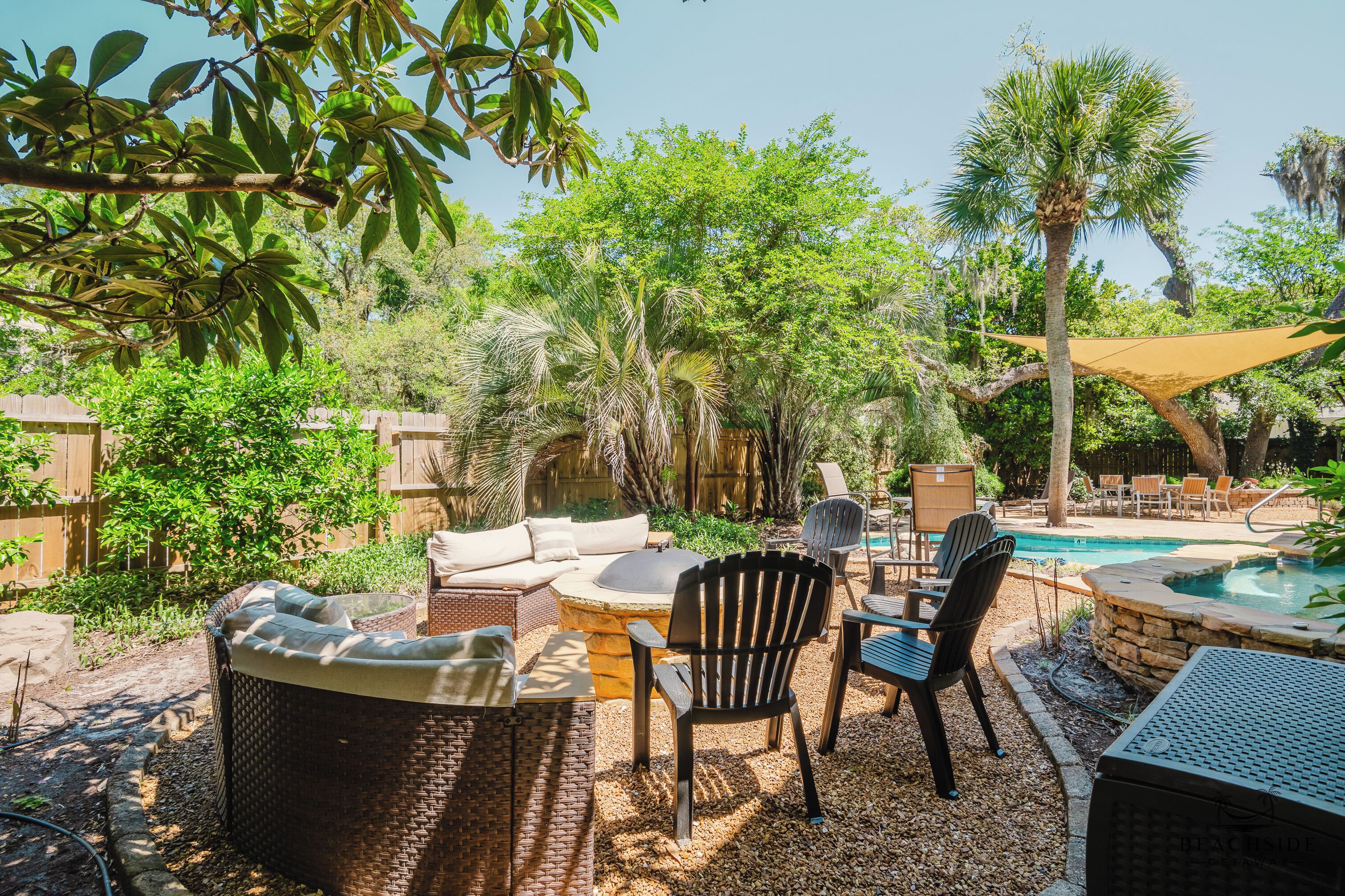 Une terrasse extérieure aménagée avec des meubles en osier, un foyer en pierre et une piscine.