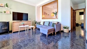 Uma sala de estar moderna com televisão de tela plana, sofá e ventilador de teto.