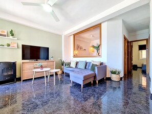 Ein modernes Wohnzimmer mit Flachbildfernseher, Sofa und Deckenventilator.