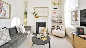 A living room with a fireplace, a sofa, a coffee table, and a bookshelf.