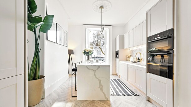 A modern kitchen with white cabinetry, a marble island, and a large window. - 2 Bed Luxury Chelsea Townhouse Sleeps 5 (London)