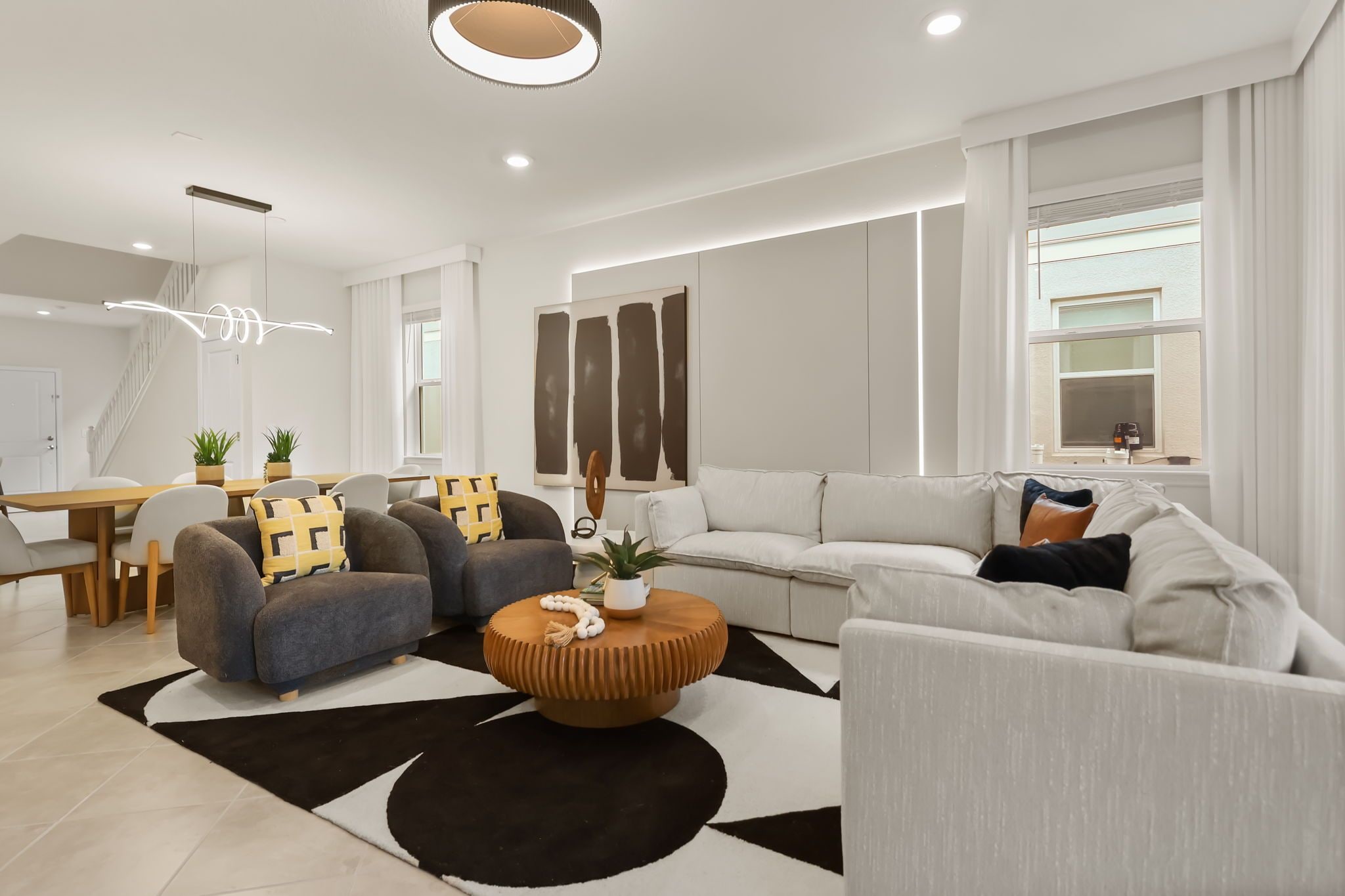 A modern living room with a sofa set, a coffee table, and a dining area with a table and chairs.