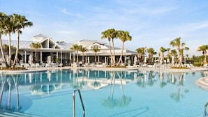 Ein Pool mit Liegestühlen und Palmen, umgeben von einem Gebäude im modernen Stil.