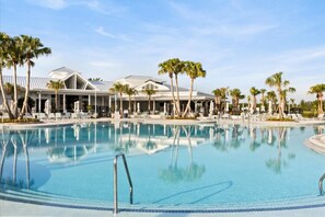Ein Pool mit Liegestühlen und Palmen, umgeben von einem Gebäude im modernen Stil.