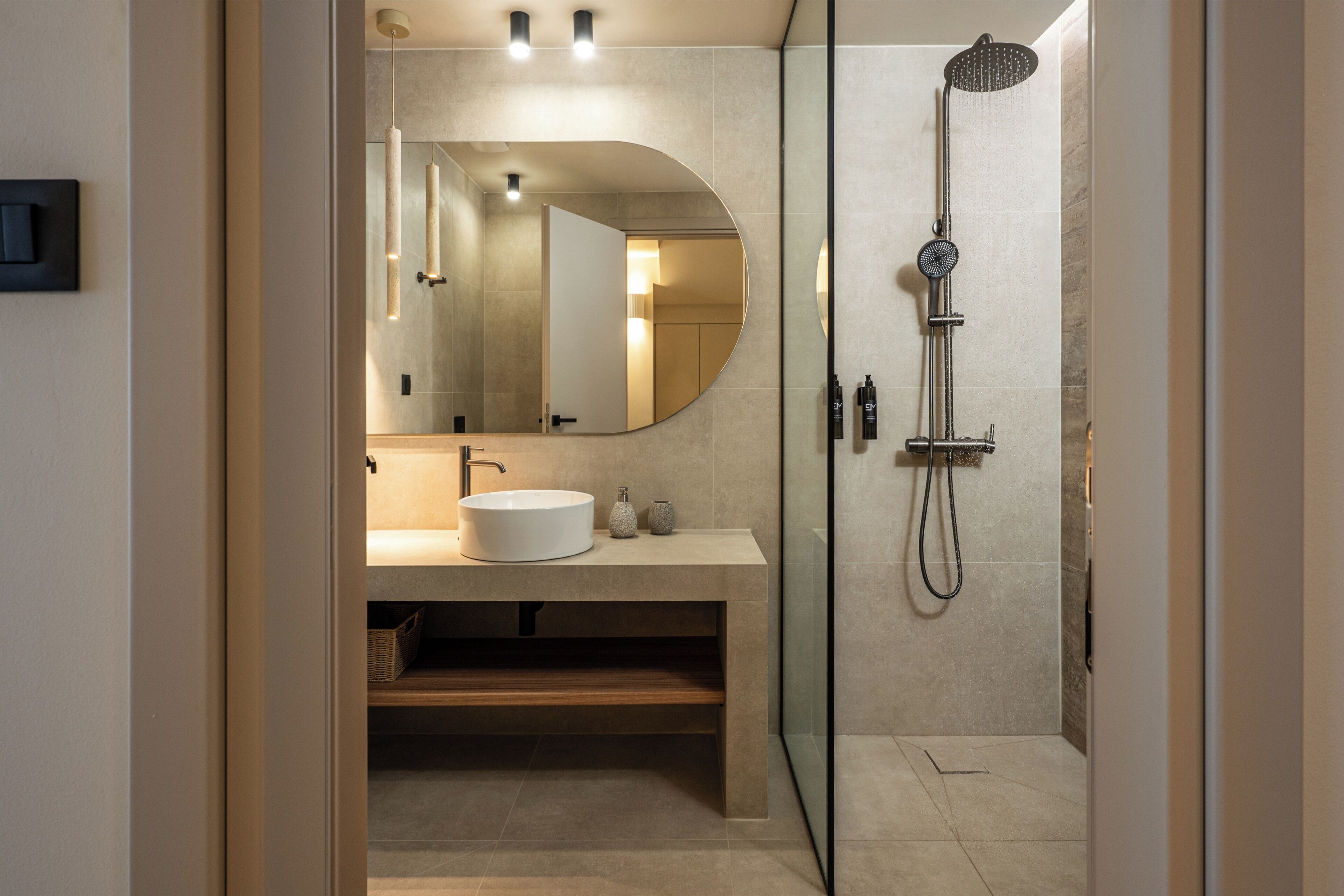 Une salle de bain moderne avec un miroir rond, un lavabo rond et une douche.