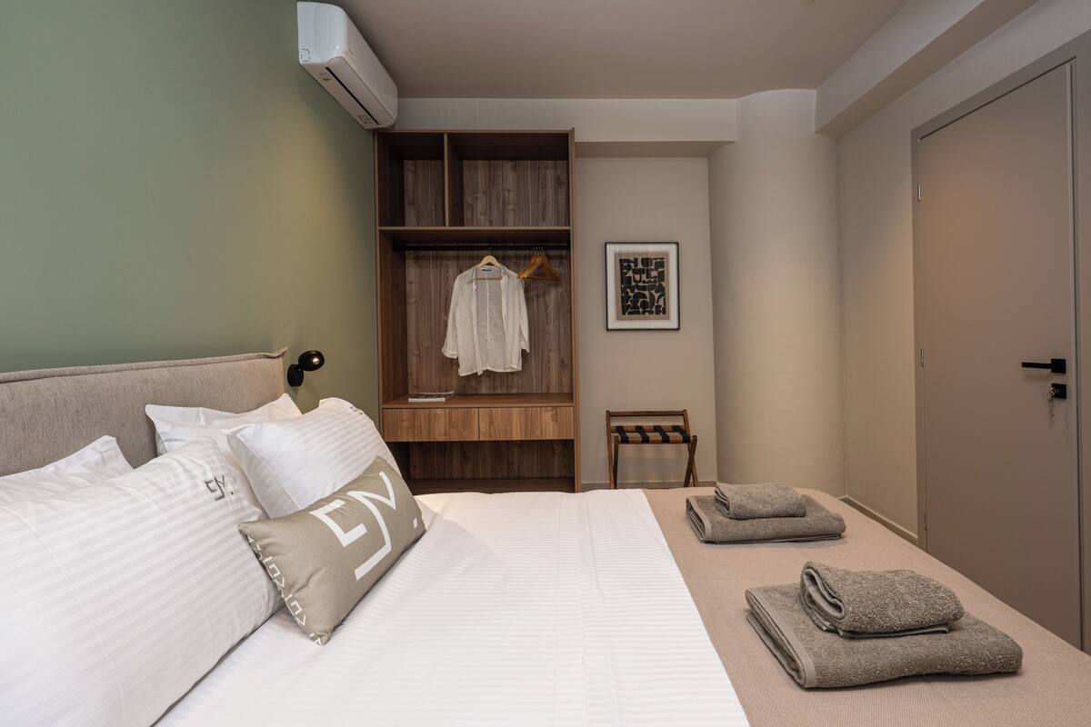 Ein Schlafzimmer mit einem Bett, einem Holzschrank, einer Bank und einem gerahmten Bild an der Wand.