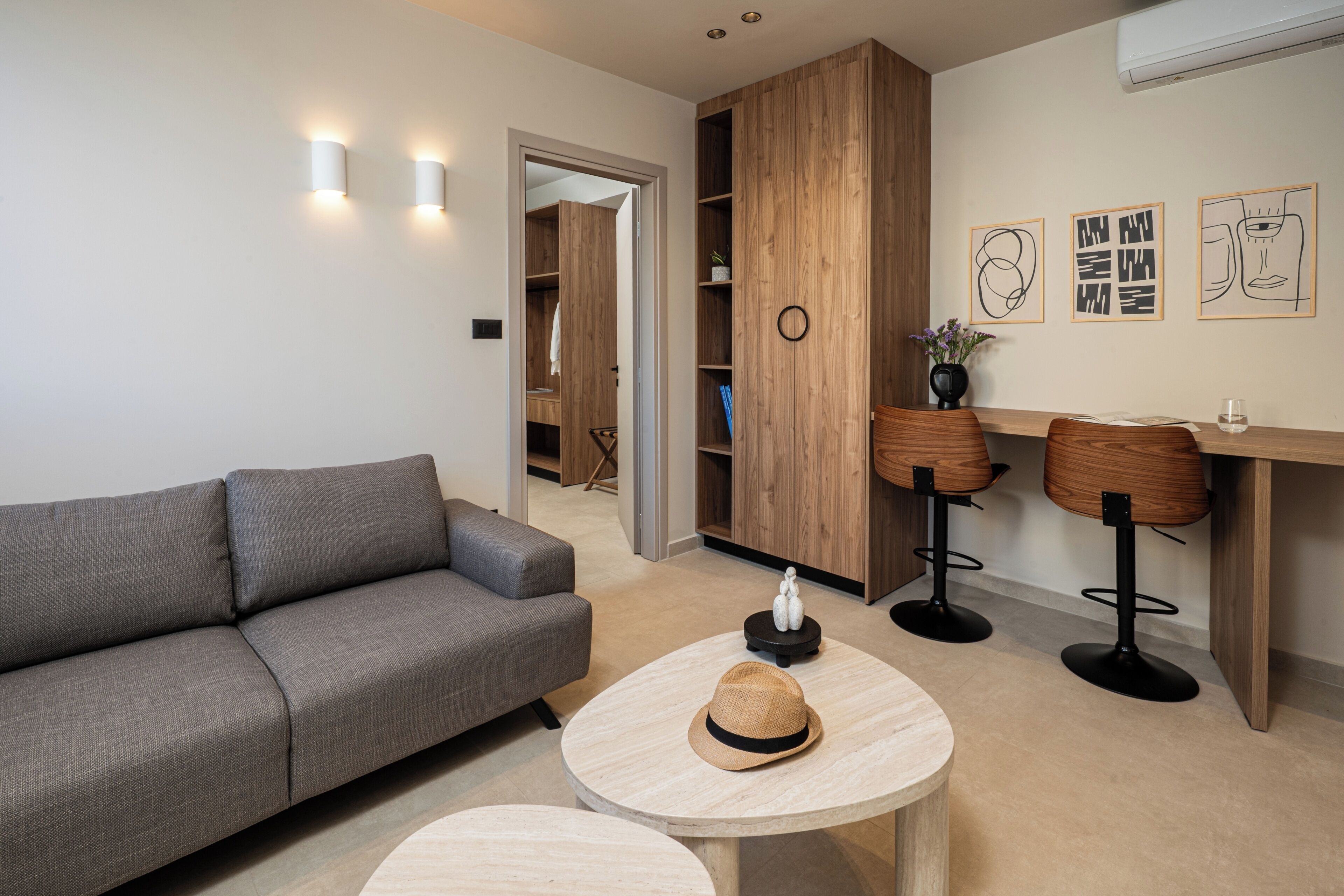 Una sala de estar moderna con un sofá gris, mesas redondas de madera y un mueble de madera con estantes.