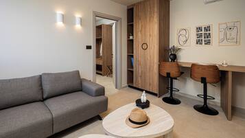 Una sala de estar moderna con un sofá gris, mesas redondas de madera y un mueble de madera con estantes.